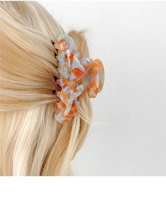 Detail view of large amber tulip hair claw clip holding hair in place for styling