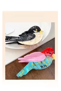 Detailed view of bird-shaped acetate hair claws in marble and colorful patterns