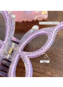 Macro view of iridescent butterfly hair claw with purple rhinestones and pearl details
