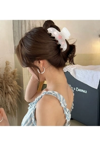Vue détaillée d'une pince à cheveux blanche translucide à étoiles roses portée par un modèle