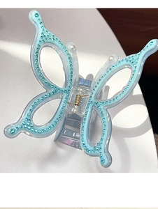 Macro shot of butterfly hair claw clip with blue rhinestones and white pearl details
