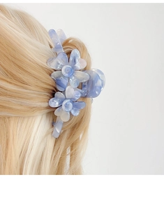 Détail d'une grande pince à cheveux fleur à motif marbré bleu et blanc sur cheveux blonds