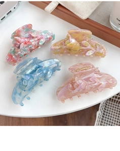 Close-up of four floral acetate hair claws with 3D tulip design on a white desk