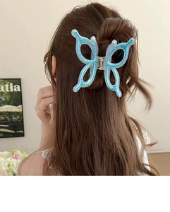 Detail view of a large blue butterfly hair claw clip with rhinestones worn on hair