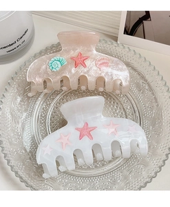 Détail de pinces à cheveux en acétate rose et blanc avec étoiles de mer et coquillages