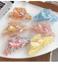 Detailed set of six colorful tulip hair claws in glossy acetate material on a white desk