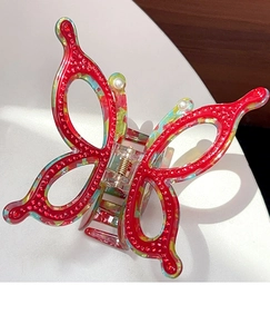 Close-up of a large red butterfly hair claw clip with pearls and sparkling rhinestones