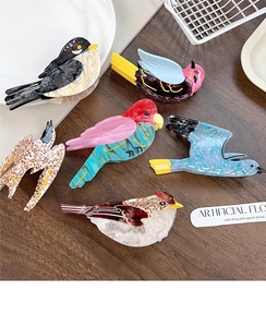 Artistic bird-shaped hair claws made of premium acetate displayed on a wooden surface