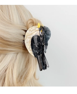 Detail of bird-shaped acetate hair claw clip with black and white marble texture on blonde hair