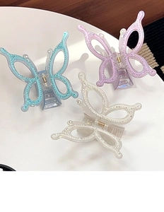 Detailed view of three oversized butterfly hair claws with rhinestones and pearl finish