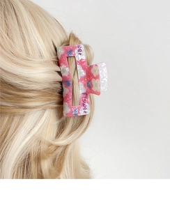 Detailansicht einer rosa quadratischen Haarklammer mit Blumen- und Schmetterlingsdruck