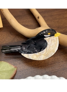 Detailed side view of bird shaped acetate hair claw with marble texture on wood