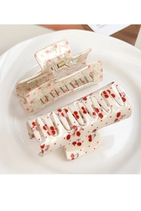 Detailopname van crème vierkante haarklemmen met bloemen- en kerspatronen op keramisch bord