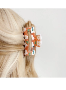 Detailansicht einer orangefarbenen Haarklammer mit Blumenmuster und Flower Aufdruck