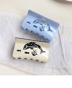 Detail view of light blue and beige acetate ocean pattern shark hair clips on paper