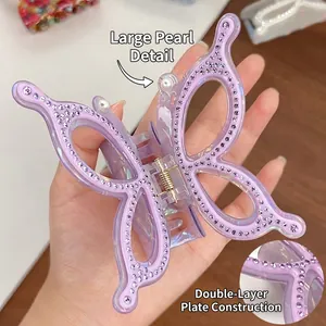 Handheld view of a large purple butterfly hair claw clip with pearls and rhinestones