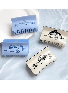 Detailed top view of ocean themed hair claws with dolphin and seashell patterns