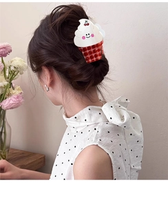 Detail of cute ice cream shaped hair claw clip with smiley cherry on model's dark hair