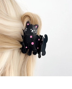 Détail d'une pince à cheveux chat noire à pois roses portée sur des cheveux blonds