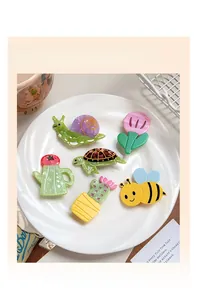 Close-up of cute acrylic hair clips featuring cartoon snail and turtle designs in a dish