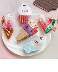 Detail view of five assorted ice cream and watermelon shaped hair claw clips on a ceramic plate