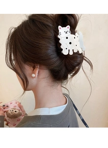 Vue arrière d'une pince à cheveux chat blanche à pois noirs sur un chignon de cheveux