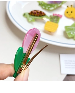 Close-up of pink tulip hair clip with green leaf base showing side detail and metal spring