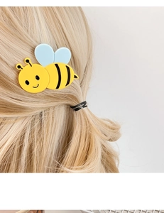 Close-up of a cute yellow bee hair clip with blue wings on blonde hair