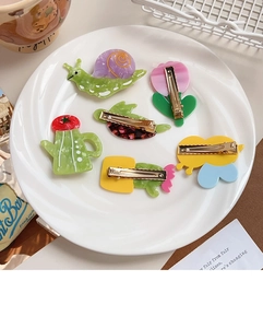 Detail of 5-piece cartoon hair clip set with metal duckbill clips on ceramic plate