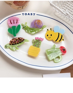 Detailed view of colorful acetate cartoon hair clips in honeybee and turtle designs