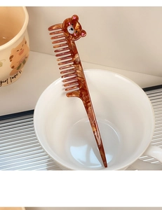 Detail of tortoise shell hair comb with cartoon bear handle in a ceramic cup