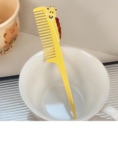 Detailed view of yellow giraffe cartoon hair comb in a ceramic cup for styling