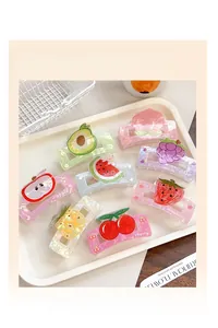 Flat lay of eight fruit-themed hair claws with translucent pearly finish in a white tray
