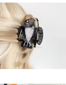 Detailed close-up of a black bird hair claw clip styled on blonde hair with marble texture