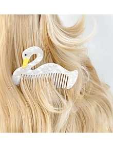 Detail of white marble texture acetate swan hair comb on golden hair background