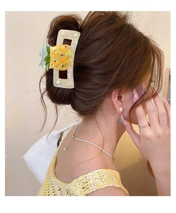 Detail of medium pineapple claw clip on hair with holographic finish and yellow fruit print