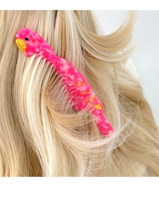 Detail view of a pink parrot acetate hair comb styled on blonde hair for women