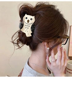 Detailed view of owl-shaped acetate hair claw clip with marble pattern in hair