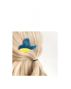 Close-up of a blue and yellow bird hair clip on hair showing acetate texture and detail