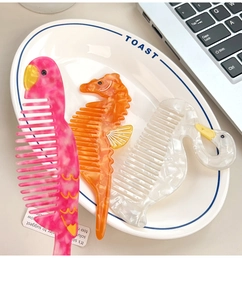Detail of colorful acetate animal shaped hair combs on a decorative white ceramic tray