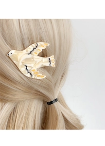 Detail of bird-shaped acetate hair clip with marble texture on blonde hair side