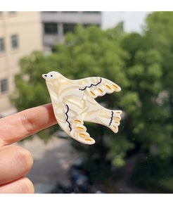 Close-up of a bird-shaped acetate hair clip with elegant stone texture and orange accents