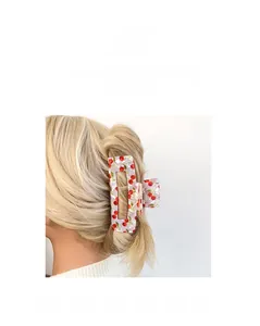 Vista dettagliata di una pinza per capelli rettangolare bianca con motivo a ciliegia