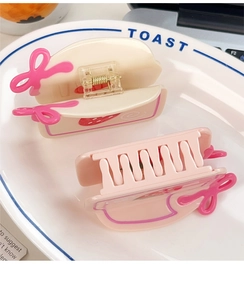 Gros plan de pinces à cheveux gâteau aux fraises avec nœuds roses sur une assiette