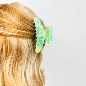 Detail showing a green starfish hair claw with white pearl accents on golden hair