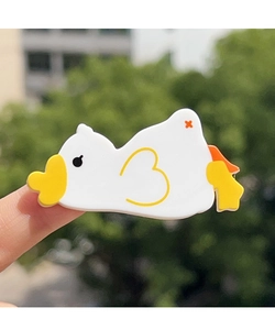 Close-up of cute duck acetate hair clip accessory being held in hand outdoors