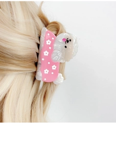 Detail der süßen Haarspange aus Acetat mit rosa gepunktetem Hundedesign am blonden Haar
