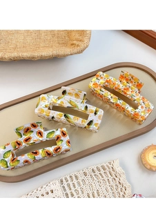 Dettaglio macro di grandi mollette rettangolari con stampe di frutta e finitura perlata
