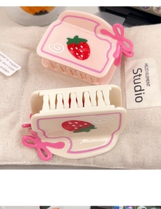 Détail d'une pince à cheveux toast fraise avec nœud rose et finition en acétate crème