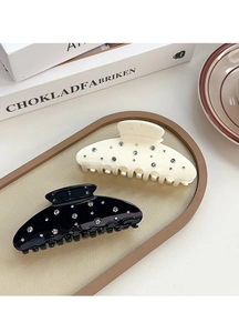 Detailed view of elegant black and cream hair claws featuring sparkling inlaid rhinestones